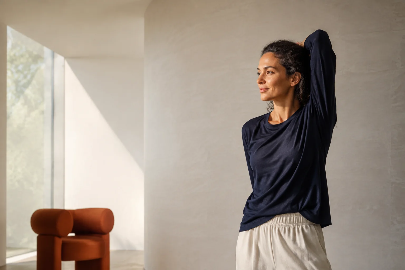 Femme effectuant un étirement doux dans un intérieur lumineux